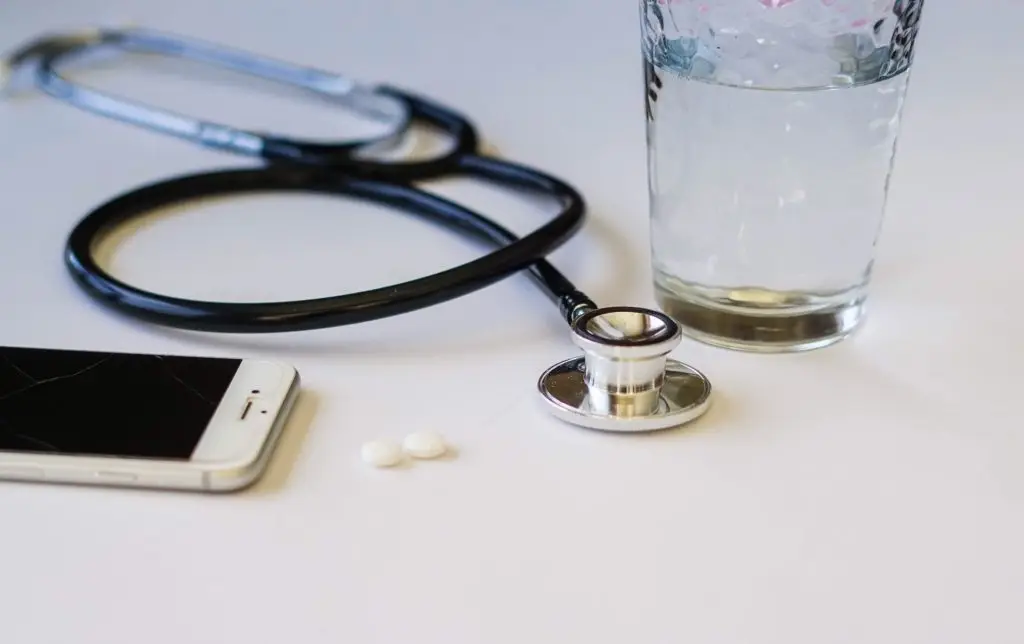 Closeup of a stethoscope, aspirin, glass of water and a mobile phone