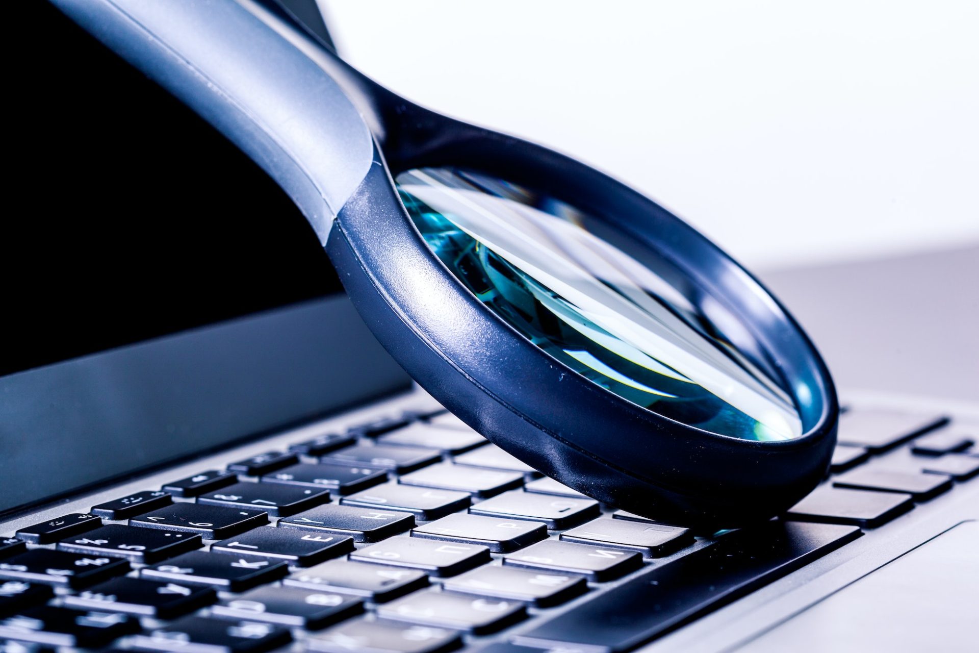 Closeup images of magnifying glass on laptop keyboard